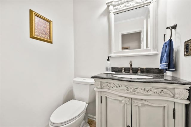 half bathroom featuring toilet, ornamental molding, and vanity