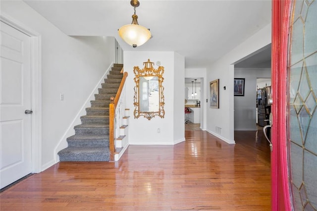 entrance foyer featuring stairs, visible vents, wood finished floors, and baseboards