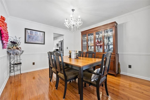 dining area featuring an inviting chandelier, light wood-style flooring, crown molding, and baseboards