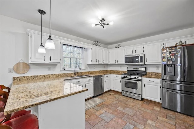 kitchen with a peninsula, stainless steel appliances, stone finish floor, white cabinetry, and a sink