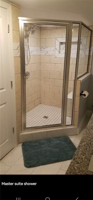 bathroom with an enclosed shower and tile patterned floors