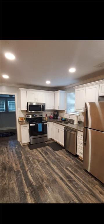 kitchen featuring ornamental molding, dark hardwood / wood-style flooring, stainless steel appliances, and white cabinets