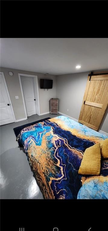 bedroom with a barn door and concrete flooring