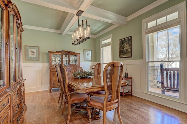 dining room with beam ceiling, a decorative wall, an inviting chandelier, and wood finished floors