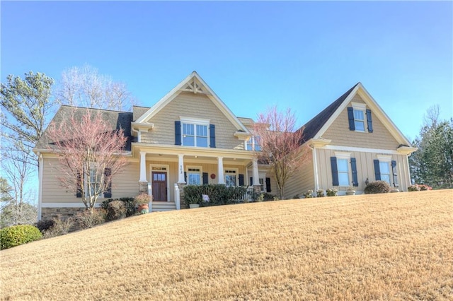 craftsman house featuring a porch, a front lawn, and board and batten siding