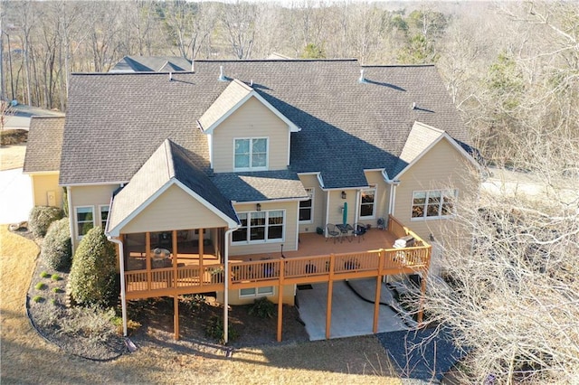 back of house featuring a shingled roof, a sunroom, and a deck