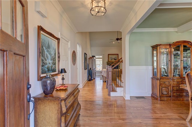 entryway with arched walkways, wood finished floors, crown molding, and stairs