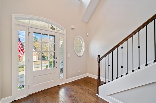 foyer featuring a healthy amount of sunlight, dark hardwood / wood-style flooring, crown molding, and a high ceiling