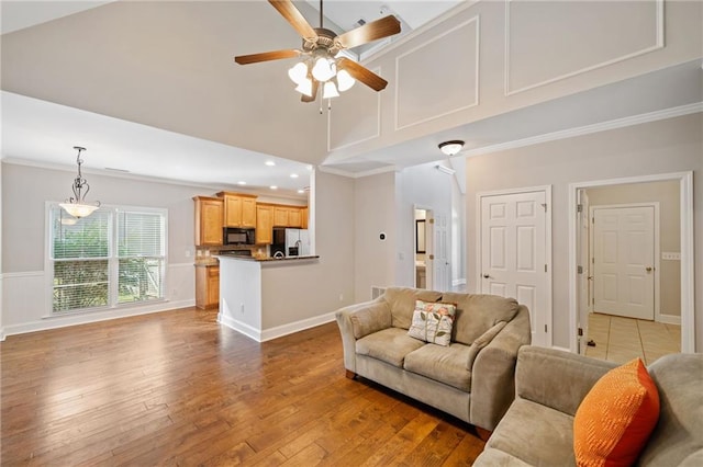 living room featuring ceiling fan, high vaulted ceiling, dark hardwood / wood-style floors, crown molding, and a fireplace