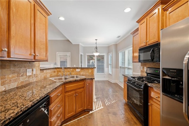 kitchen featuring backsplash, sink, black appliances, light hardwood / wood-style flooring, and hanging light fixtures