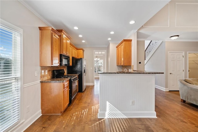 kitchen featuring sink, light wood-type flooring, decorative backsplash, black appliances, and ornamental molding