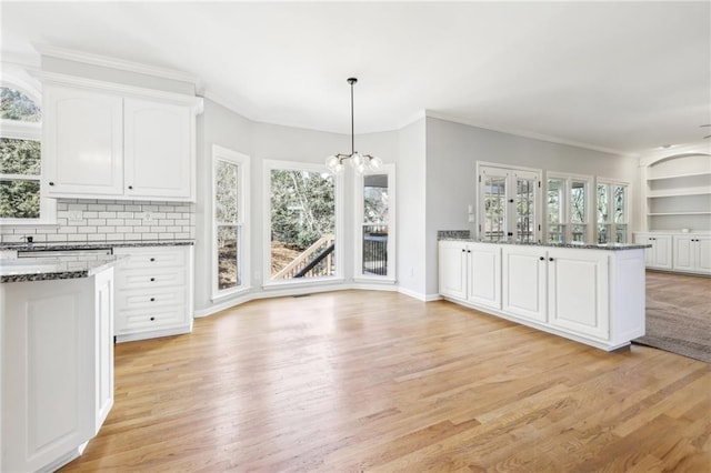 kitchen featuring a wealth of natural light, white cabinetry, light wood-style flooring, and dark stone countertops