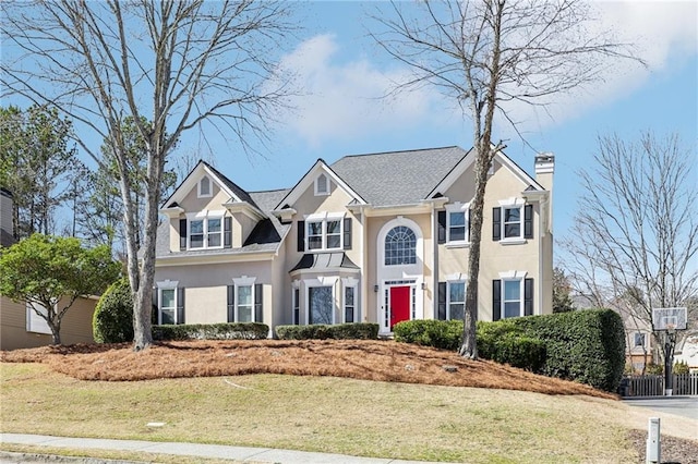 view of front of house with a chimney, a front lawn, and stucco siding