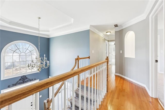 hall featuring crown molding, visible vents, light wood-style floors, an upstairs landing, and baseboards