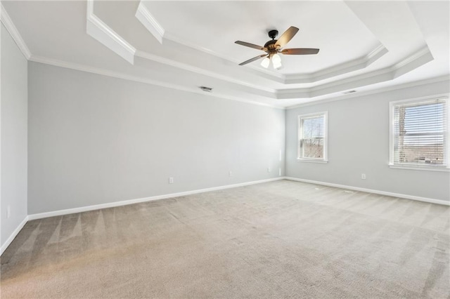 carpeted empty room with a tray ceiling, crown molding, visible vents, ceiling fan, and baseboards