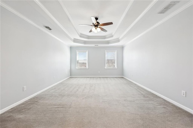 carpeted empty room with baseboards, a raised ceiling, visible vents, and crown molding