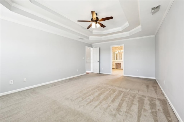 unfurnished bedroom with baseboards, ensuite bath, a tray ceiling, crown molding, and carpet floors