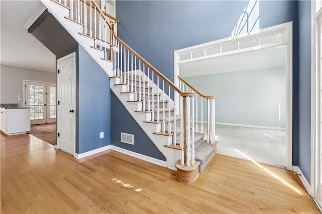 staircase featuring french doors, wood finished floors, visible vents, and baseboards