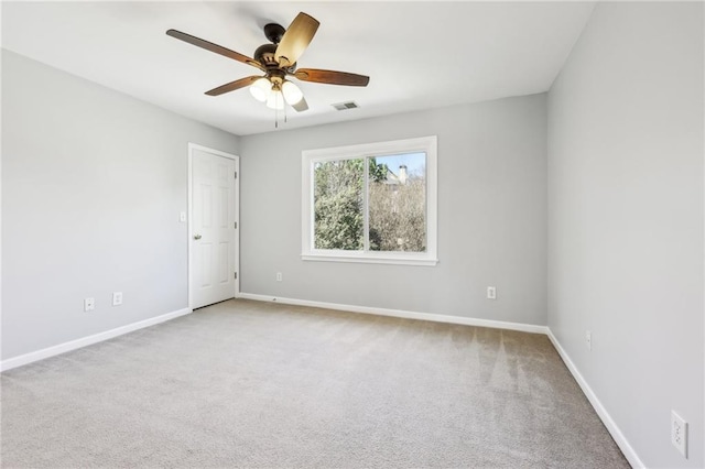 carpeted spare room featuring baseboards, visible vents, and ceiling fan