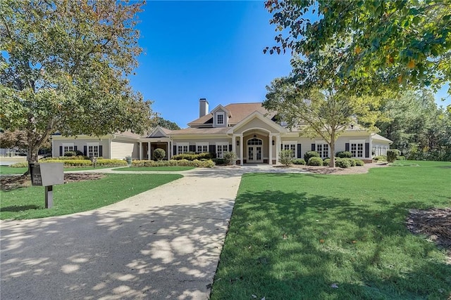 view of front of house with a front yard, a chimney, and french doors