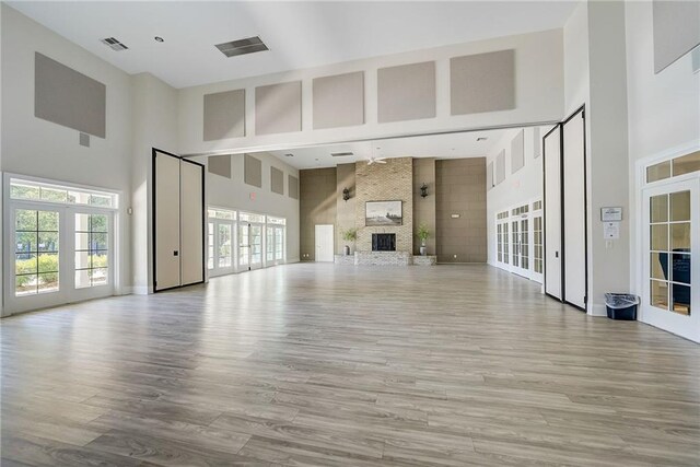 unfurnished living room with a large fireplace, french doors, light wood-type flooring, and visible vents