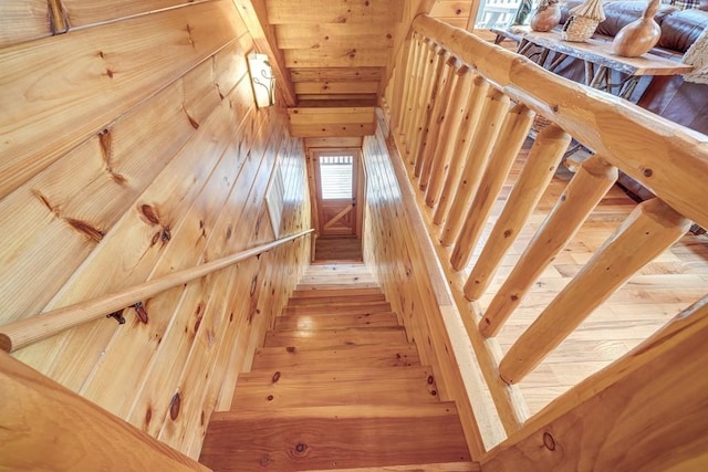 stairway with wood walls and wood finished floors