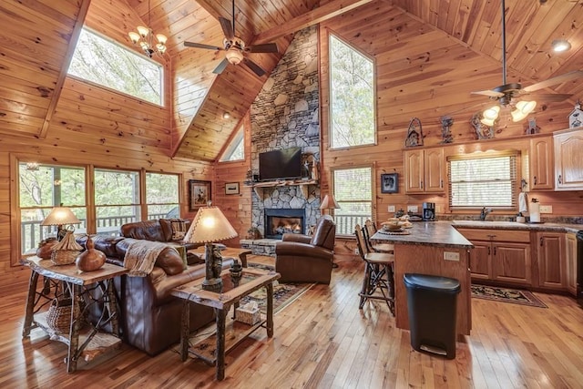 living room with a ceiling fan, a fireplace, high vaulted ceiling, wooden ceiling, and light wood-style floors