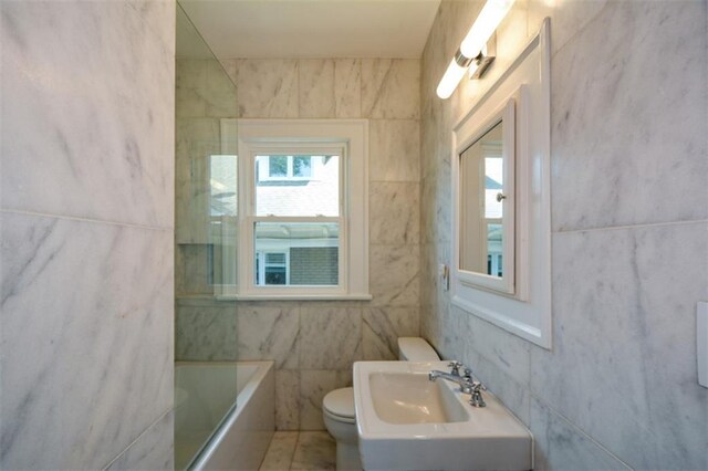 full bathroom featuring tile walls, toilet, sink, shower / washtub combination, and tile flooring