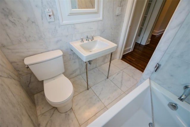 bathroom with hardwood / wood-style flooring, toilet, tile walls, sink, and a tub