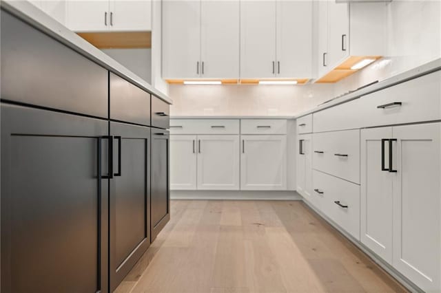 kitchen with tasteful backsplash, white cabinets, and light hardwood / wood-style floors