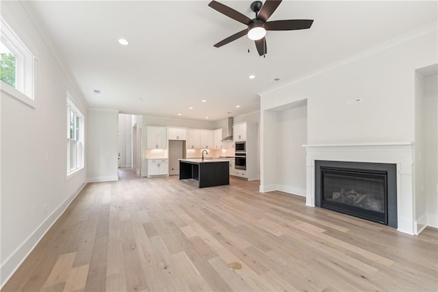 unfurnished living room with ornamental molding, ceiling fan, and light wood-type flooring