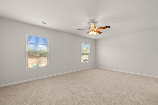 carpeted empty room with ceiling fan and a wealth of natural light