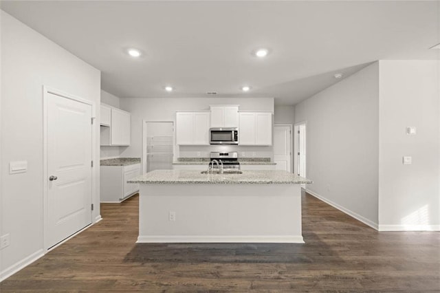 kitchen with white cabinetry, appliances with stainless steel finishes, an island with sink, and light stone counters