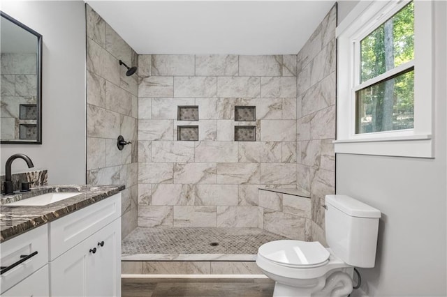 bathroom featuring tiled shower, vanity, and toilet