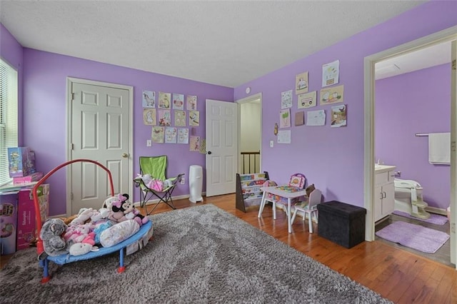 playroom featuring a textured ceiling and wood finished floors