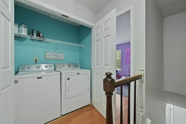 laundry area with independent washer and dryer, a textured ceiling, laundry area, and light wood-type flooring