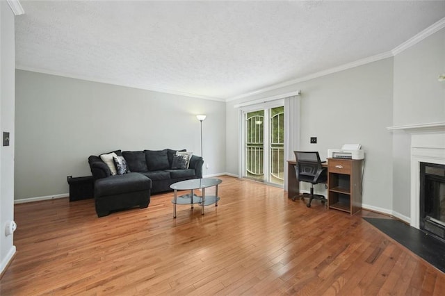living area with crown molding, a fireplace with flush hearth, a textured ceiling, and wood finished floors