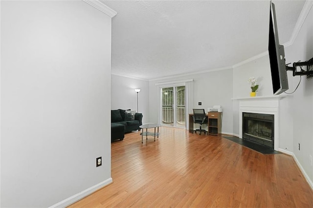 living area with crown molding, baseboards, a fireplace with flush hearth, and wood finished floors
