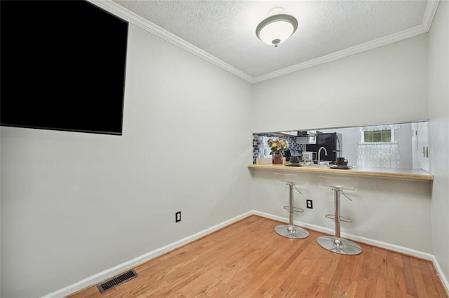 unfurnished office with baseboards, a textured ceiling, visible vents, and wood finished floors