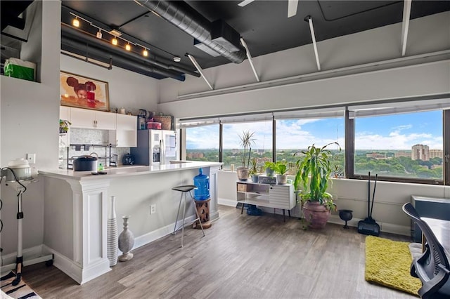 120 Ralph Mcgill Blvd NE Unit 1409, Atlanta, GA 30308 - kitchen featuring stainless steel fridge with ice dispenser, wood finished floors, white cabinets, decorative backsplash, and a peninsula