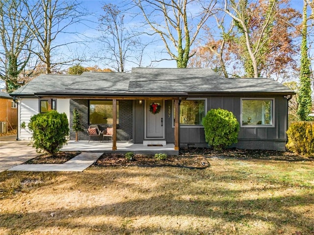 single story home with covered porch, a front yard, and board and batten siding