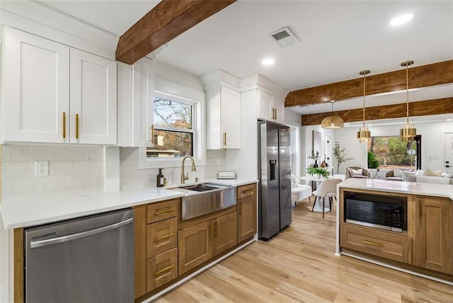 kitchen with stainless steel dishwasher, built in microwave, fridge with ice dispenser, beam ceiling, and a sink