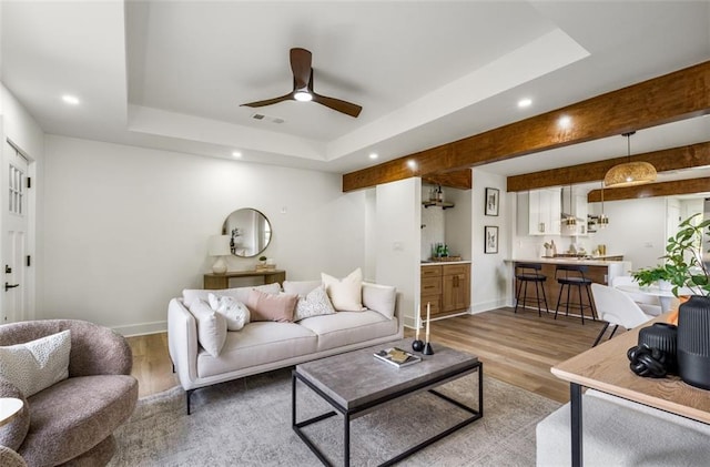 living room featuring a tray ceiling, wood finished floors, a ceiling fan, baseboards, and recessed lighting