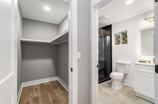 bathroom with toilet, a stall shower, vanity, and wood finished floors