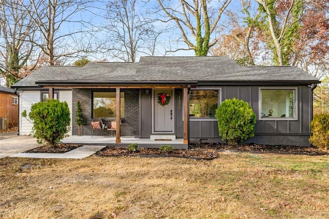 ranch-style home featuring a porch, a front yard, board and batten siding, and central air condition unit