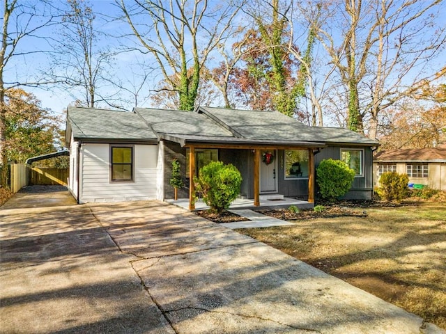 view of front of home with driveway, covered porch, and fence