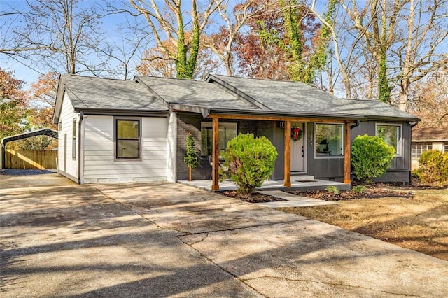 view of front of house featuring concrete driveway, covered porch, and a shingled roof