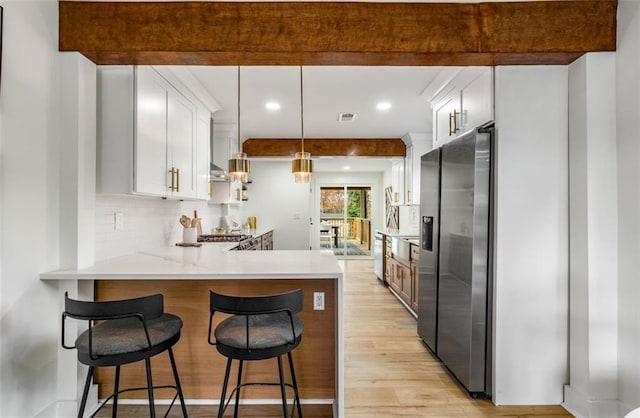 kitchen featuring stainless steel refrigerator with ice dispenser, light wood-type flooring, recessed lighting, a peninsula, and decorative backsplash