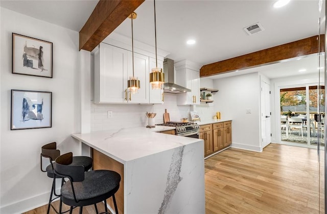 kitchen featuring wall chimney exhaust hood, gas range, baseboards, beam ceiling, and tasteful backsplash
