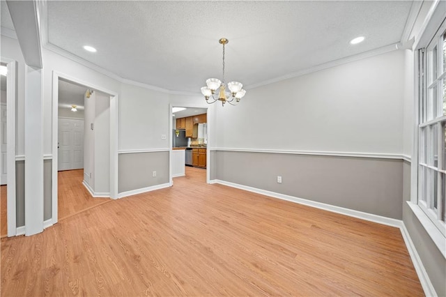 interior space with light hardwood / wood-style flooring, ornamental molding, a textured ceiling, and a notable chandelier